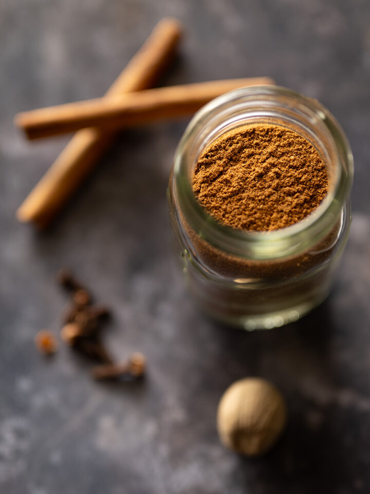 Irish mixed spice in a jar with cinnamon sticks, whole nutmeg, and whole cloves